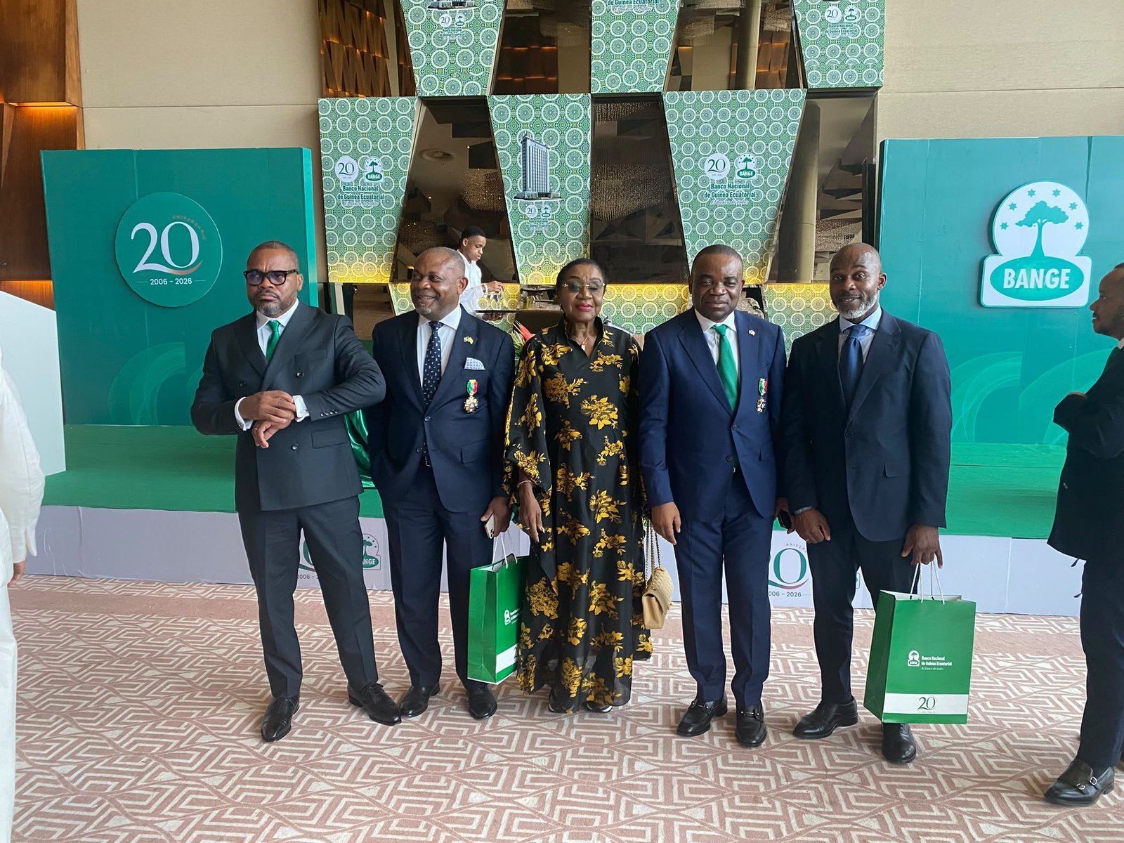 Five attendees pose in front of the green stage at BANGE's 20th anniversary celebration.