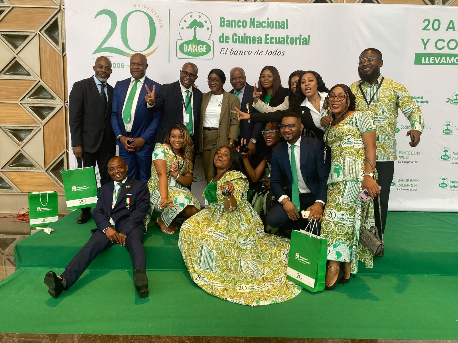 A group of attendees poses on the green carpet in front of the backdrop for BANGE's 20th anniversary.